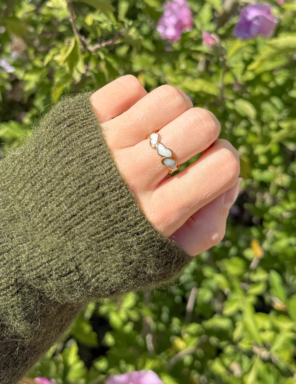 Heart ring with pastel enamel hearts on a finger