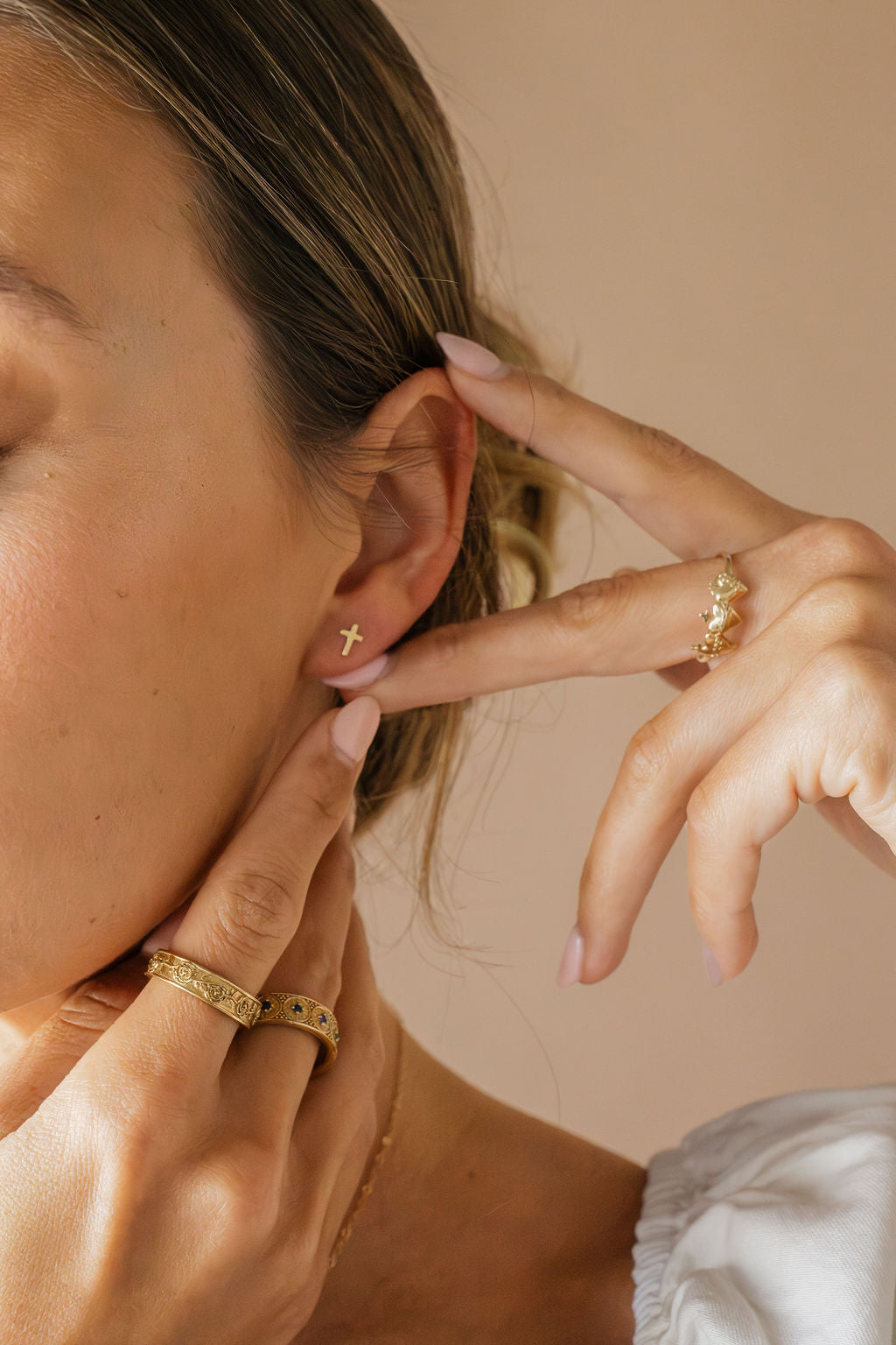 Gold cross stud earrings on model ear
