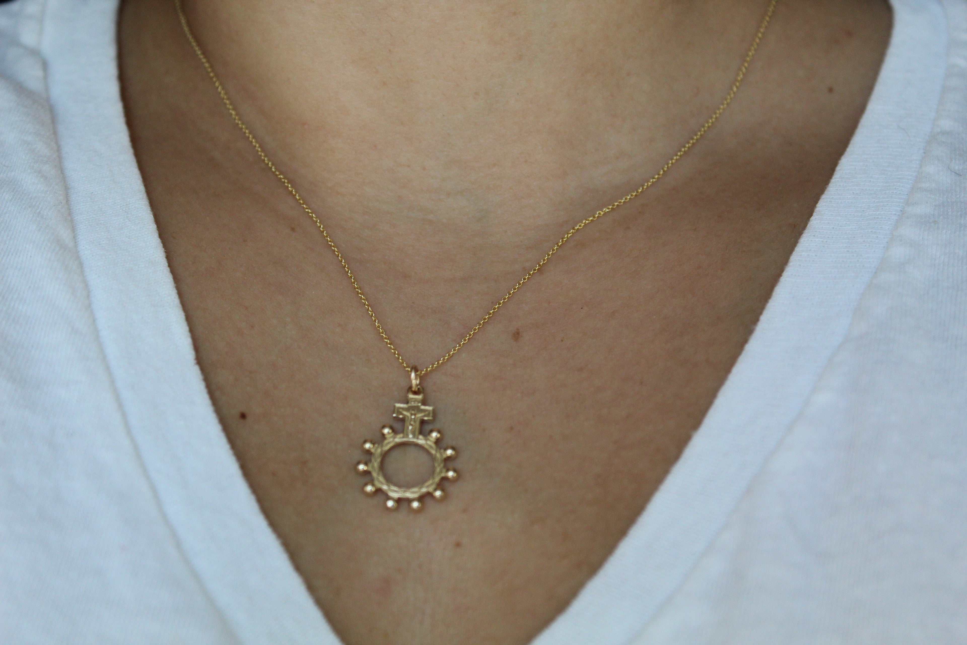 14k gold rosary bead necklace with circular sunburst-style pendant on a fine chain