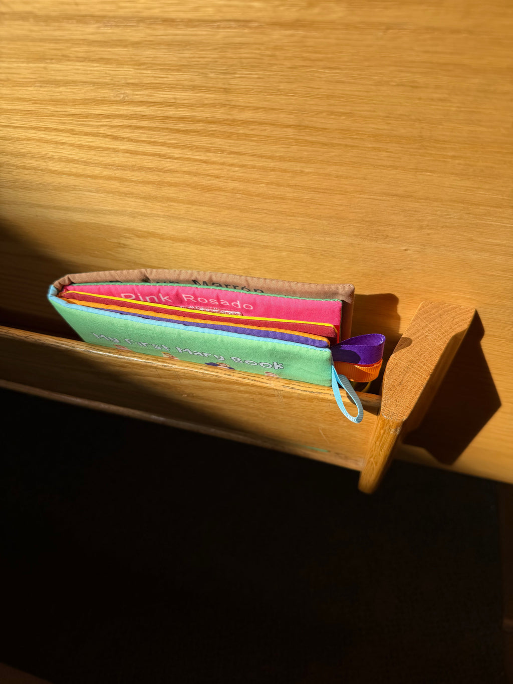 Children's board book with colorful ribbon tabs, shown side view on shelf