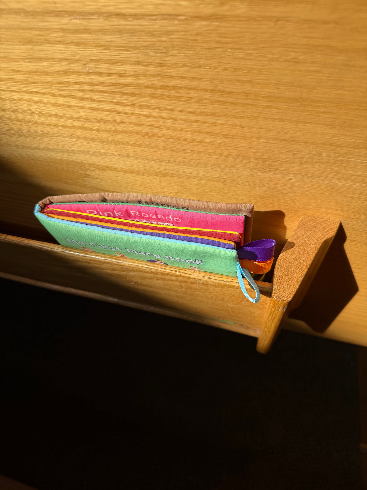 Children's board book with colorful ribbon tabs, shown side view on shelf