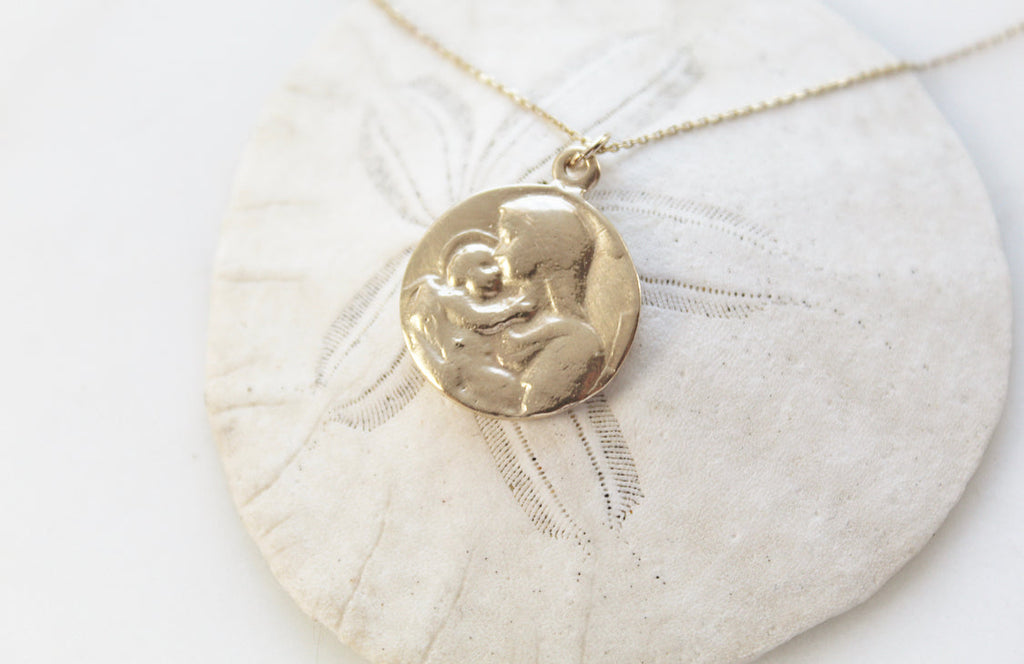14k gold medallion pendant necklace with Jesus and Mary relief, chain laid out