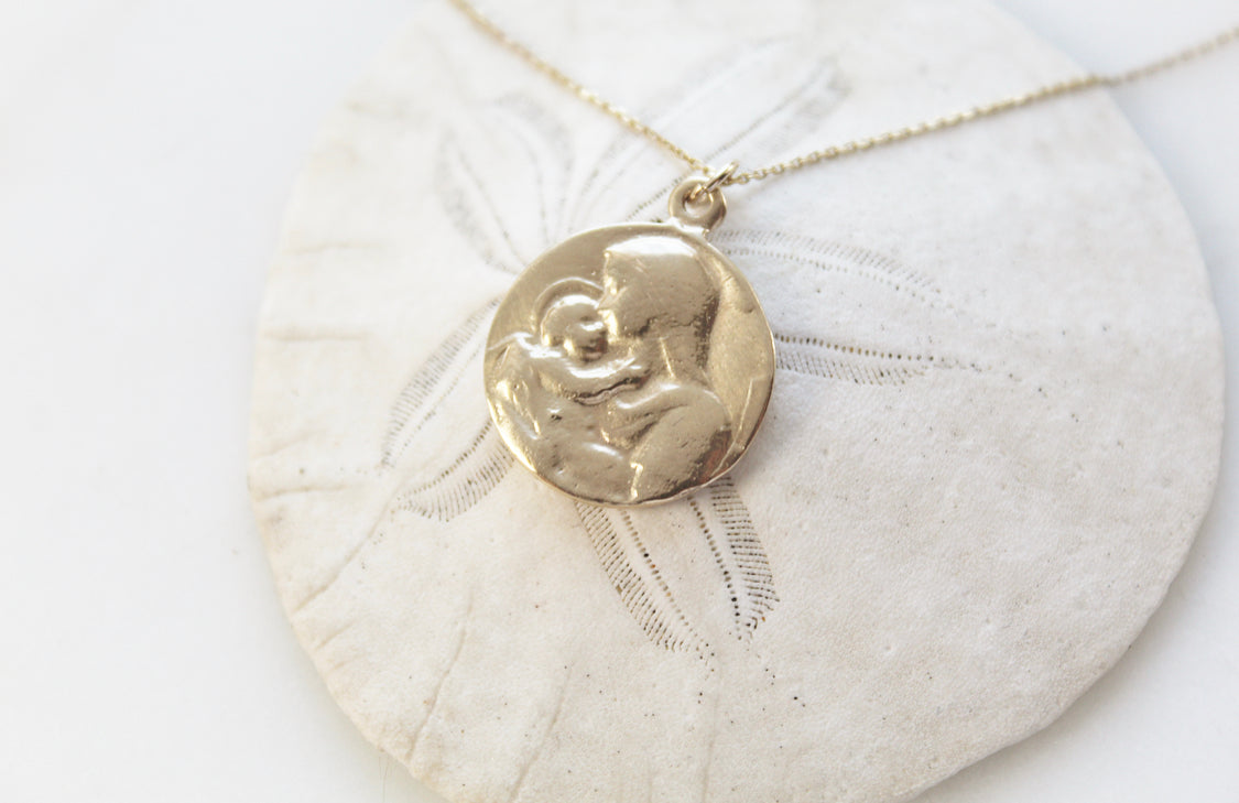 14k gold medallion pendant necklace with Jesus and Mary relief, chain laid out