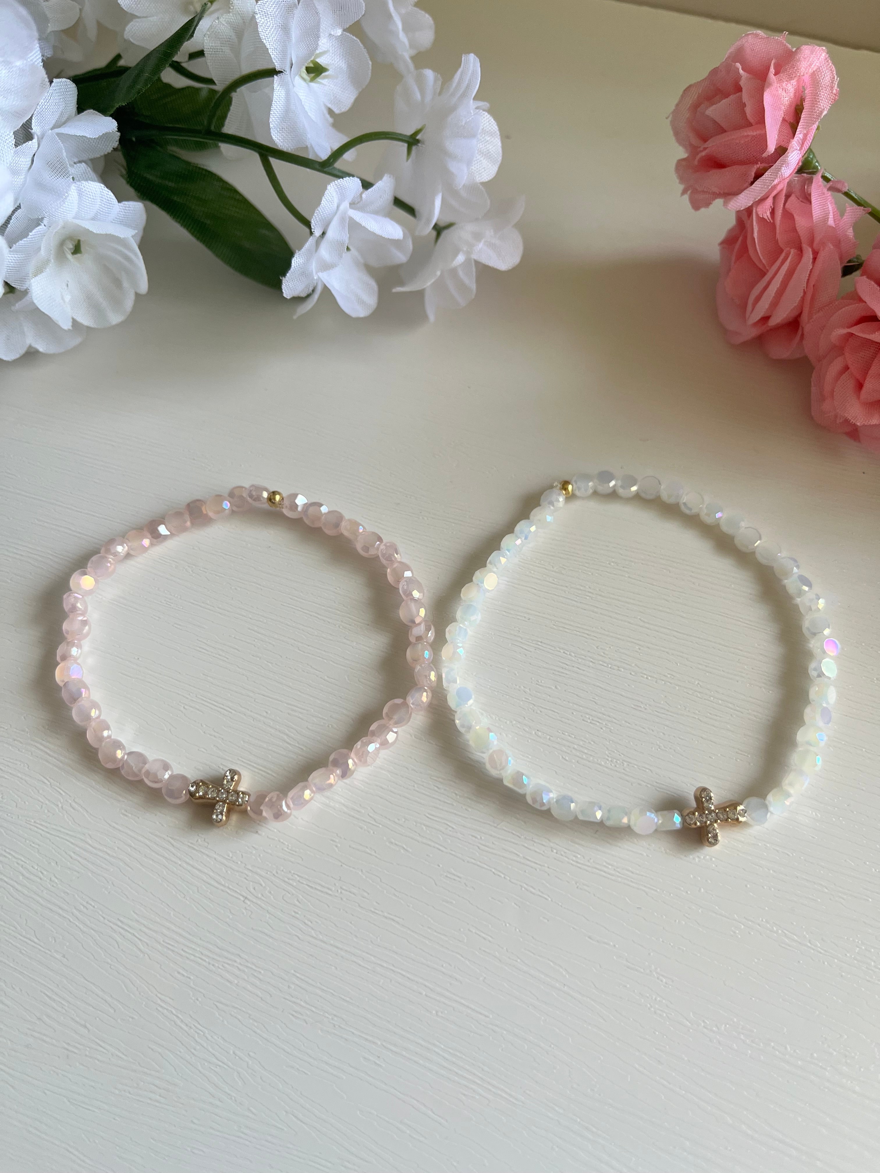 Pink and white beaded cross bracelets, each with a gold cross charm