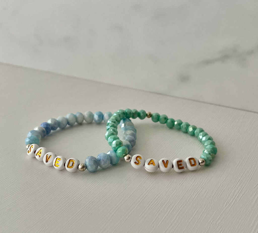 Light blue beaded bracelet with gold accents and 'SAVED' letter beads