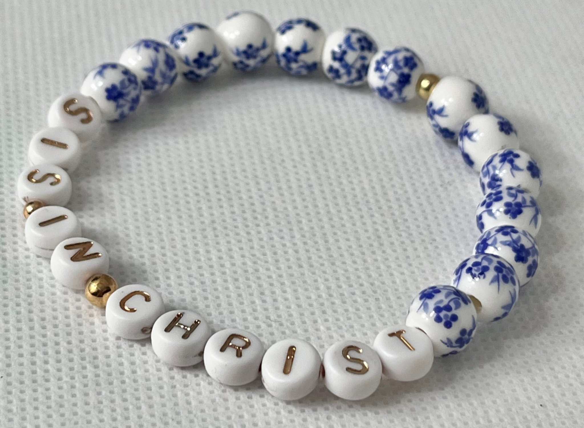 Blue bead bracelet with white letter beads spelling IN CHRIST and blue floral beads
