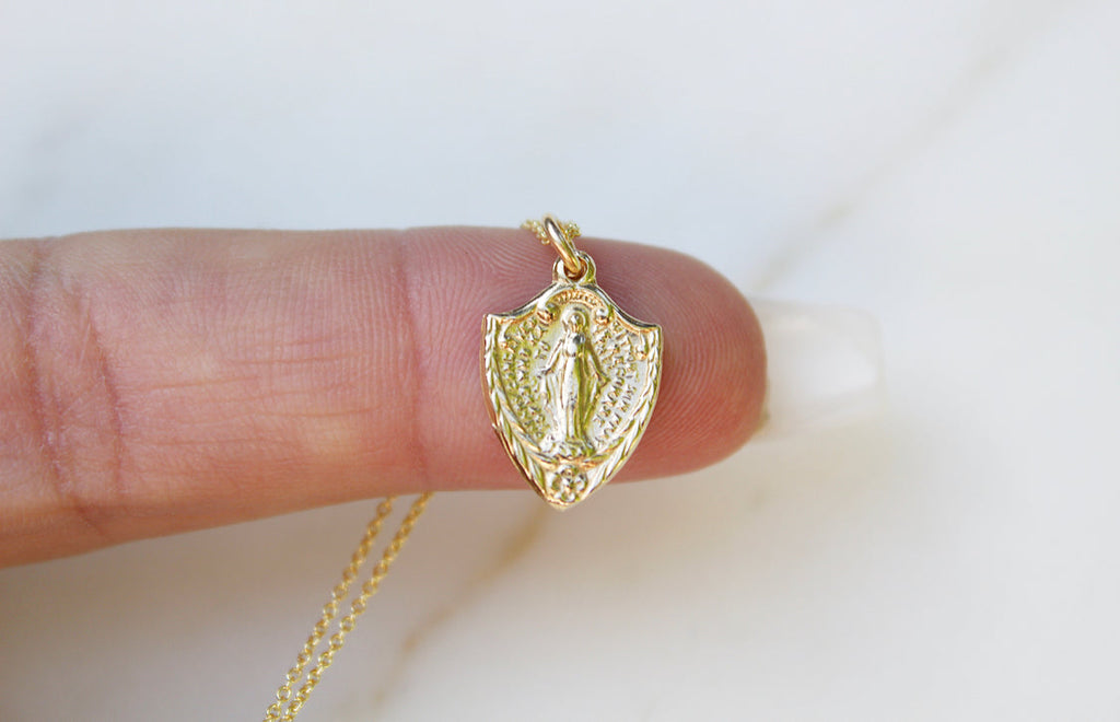 14K gold shield pendant with detailed figure, bail and attached chain