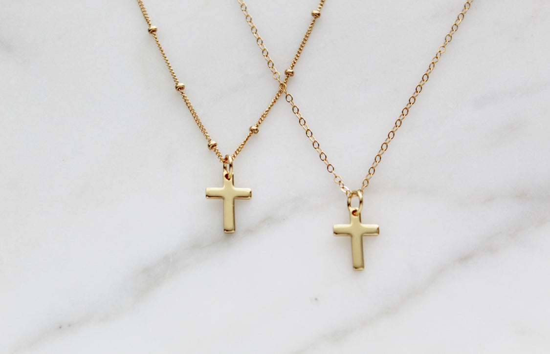 Two gold cross pendant necklaces on layered thin chains, small cross charms