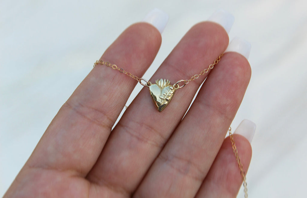 Gold-tone heart pendant necklace on an open palm view