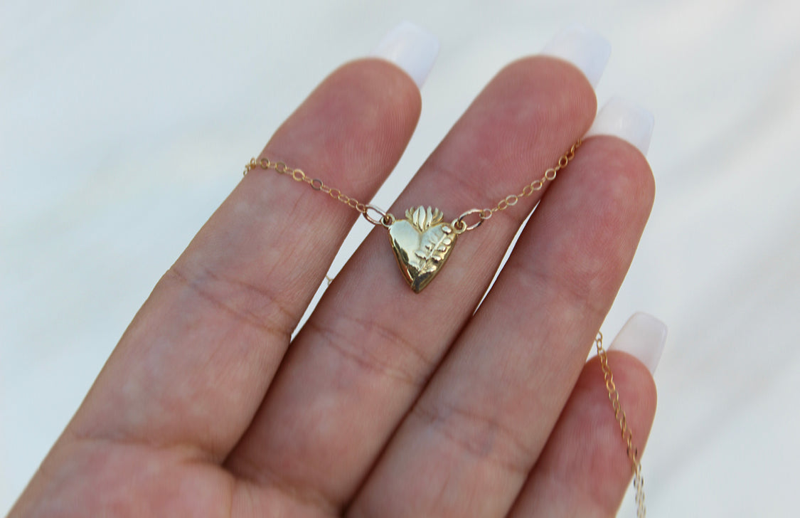 Gold-tone heart pendant necklace on an open palm view