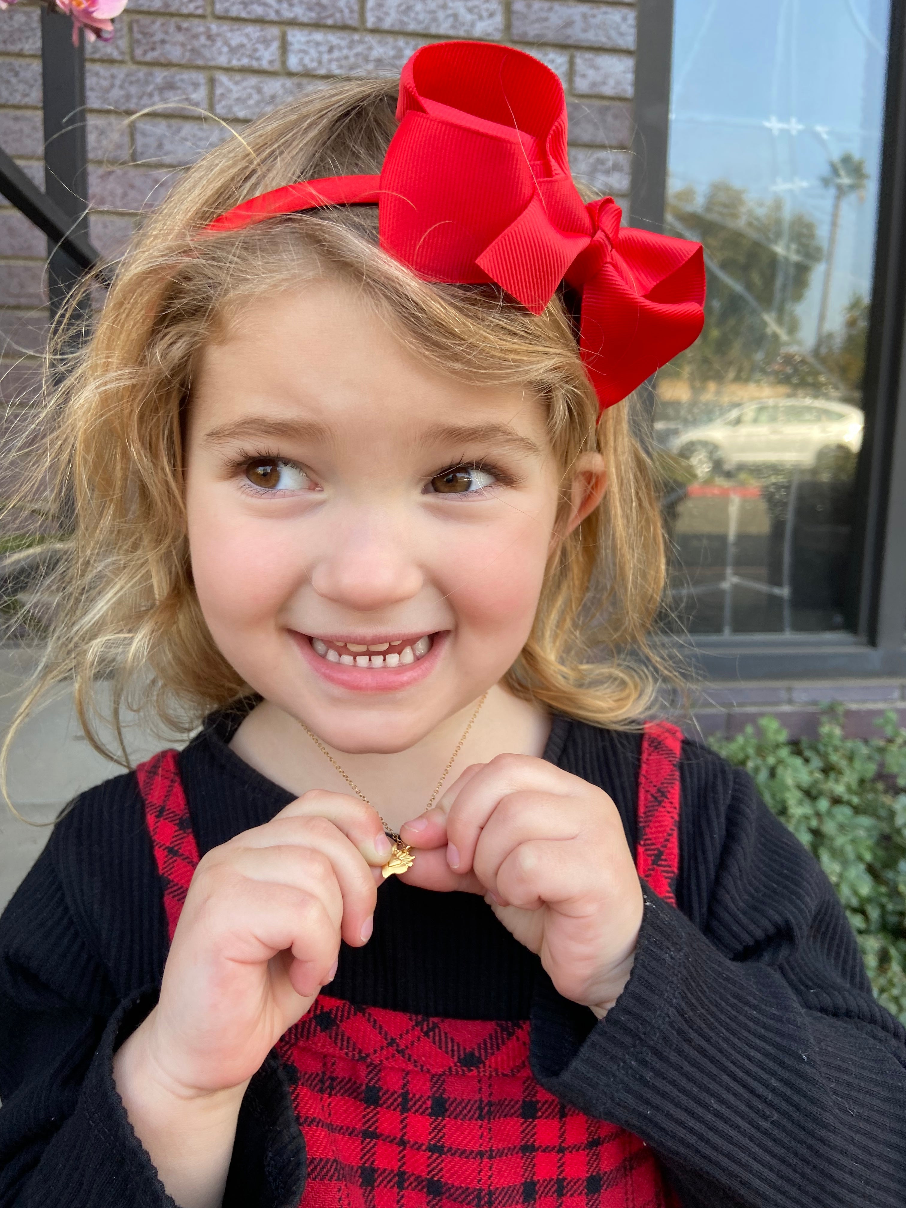 Heart charm necklace with small pendant worn by a smiling child
