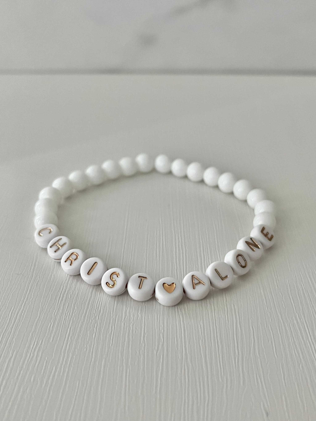 White bead bracelet with “Christ Alone” letter beads and heart detail