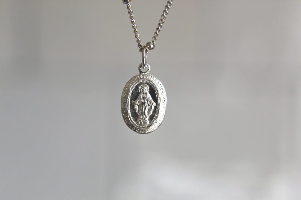 Silver miraculous medal necklace with oval pendant and figure on a chain