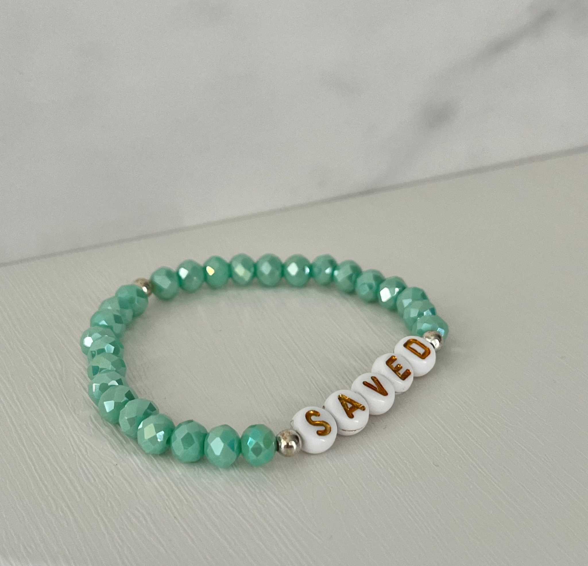 Mint green beaded bracelet with gold-accented 'SAVED' letter beads