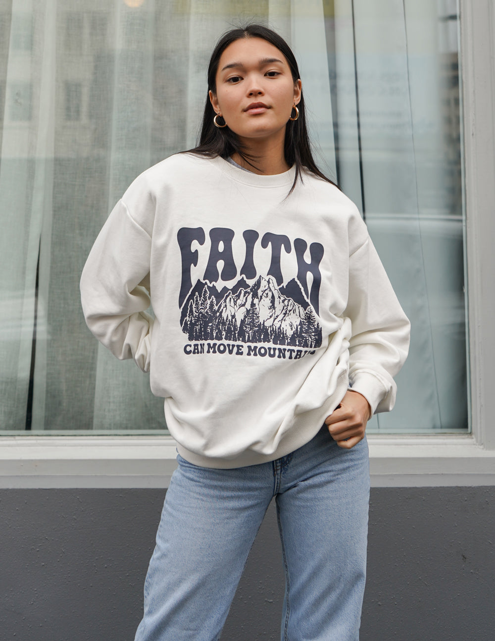 White unisex crewneck sweatshirt with dark “Faith” mountain graphic and text on chest