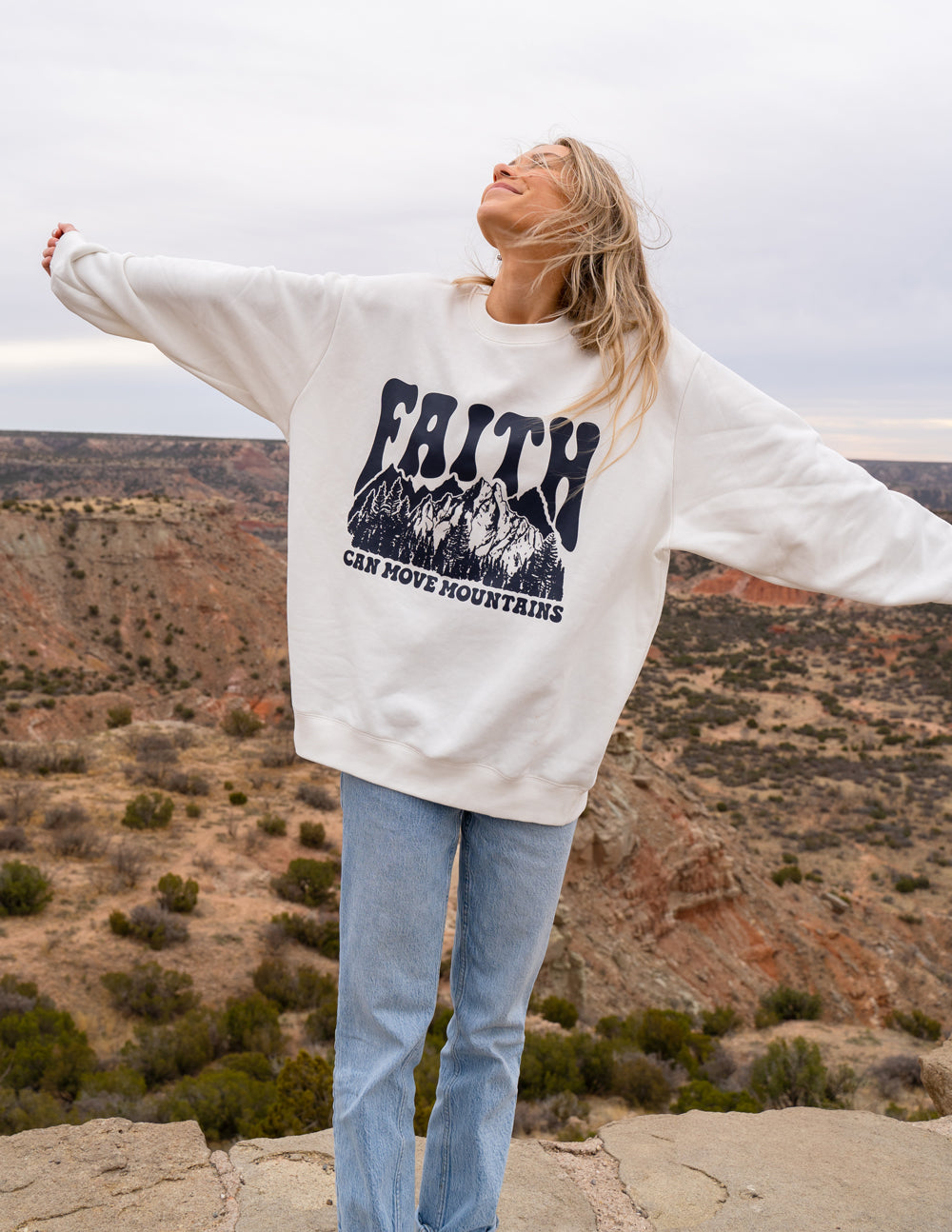 White unisex crewneck sweatshirt with dark “Faith” mountain graphic, long sleeves