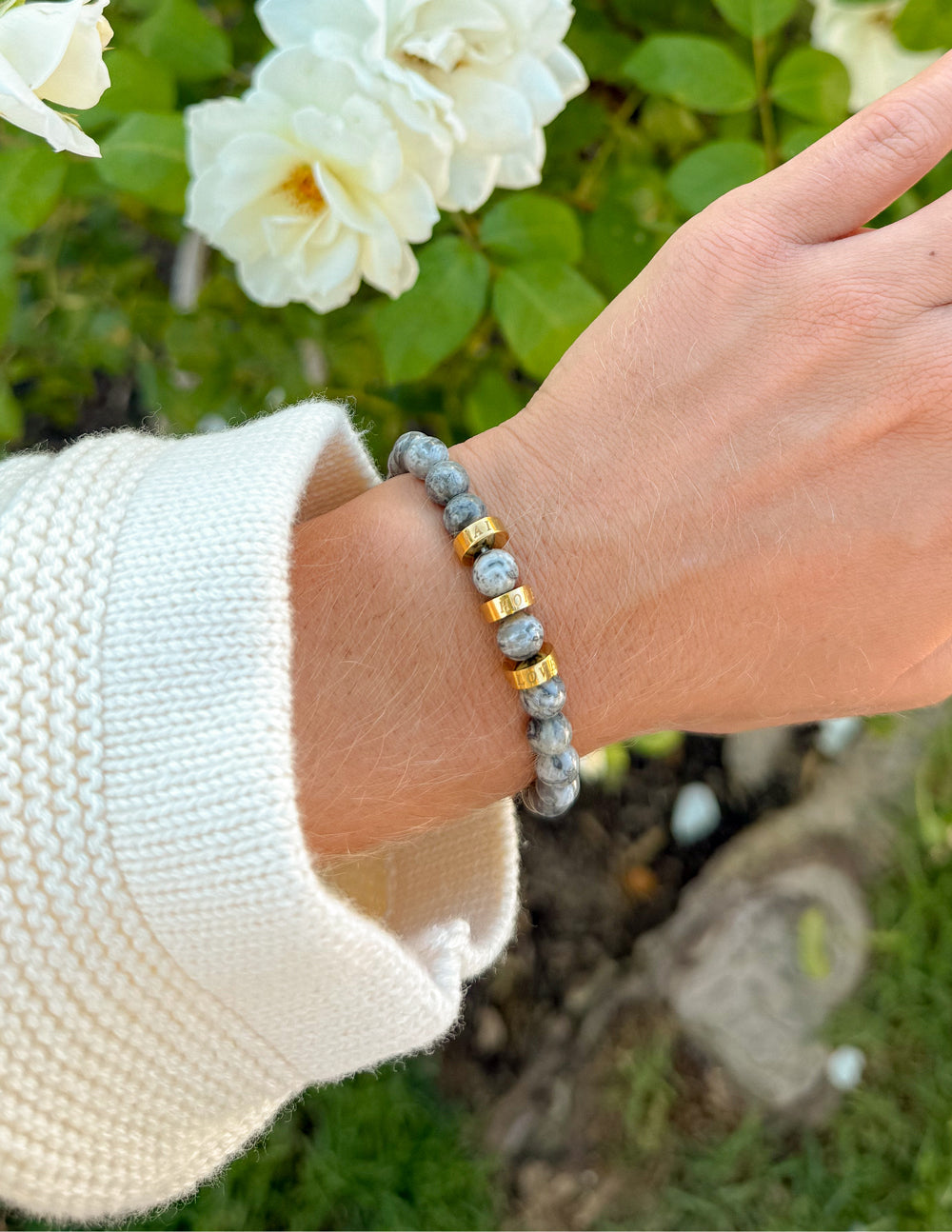 Gray stone bead bracelet with gold spacer beads on wrist