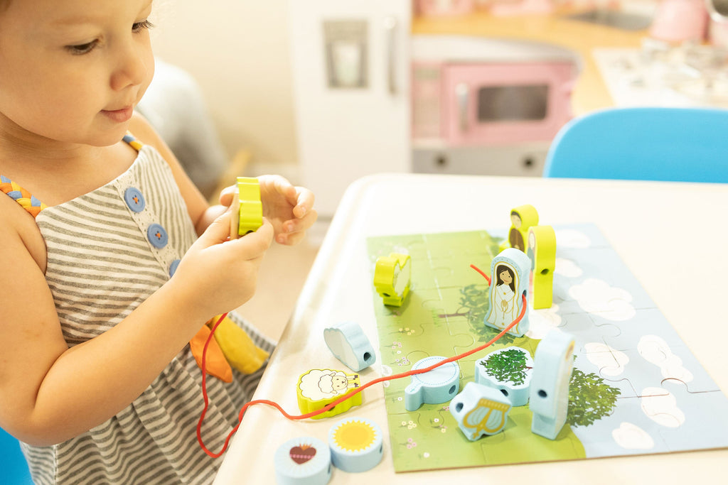 Child playing with a colorful lacing puzzle set featuring cutout figures on the board