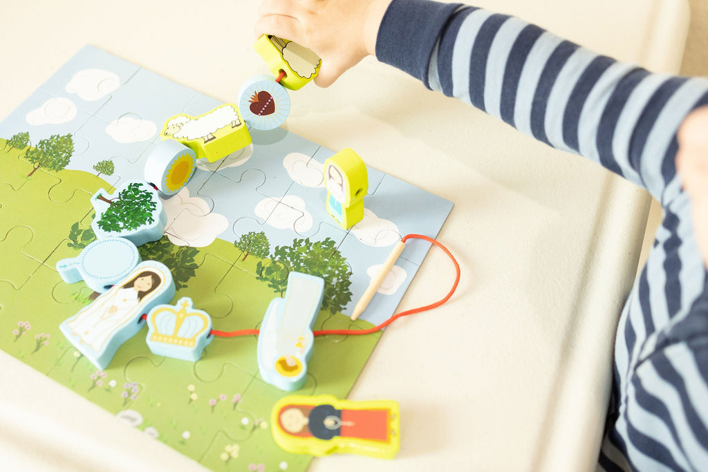 Close-up of children's lacing puzzle board with cords, pegs, and colorful pieces