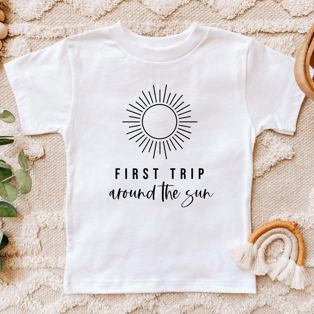 Kids white cotton tee with sunburst graphic and 'First Trip around the sun' text