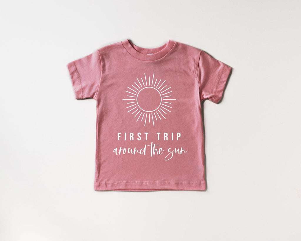 Kids rose-pink cotton tee with sunburst graphic and 'First Trip around the sun' text