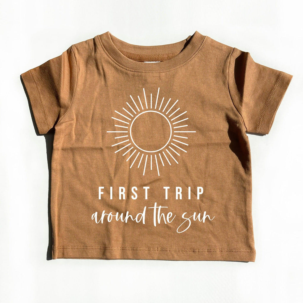Kids brown cotton tee with sunburst graphic and 'First Trip' text