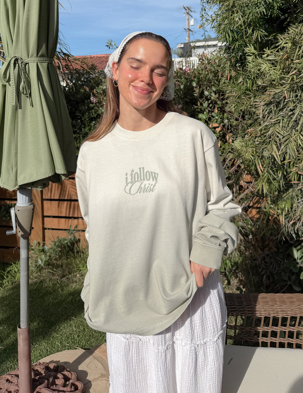 Light cream long-sleeve crewneck tee with 'i follow Christ' front graphic