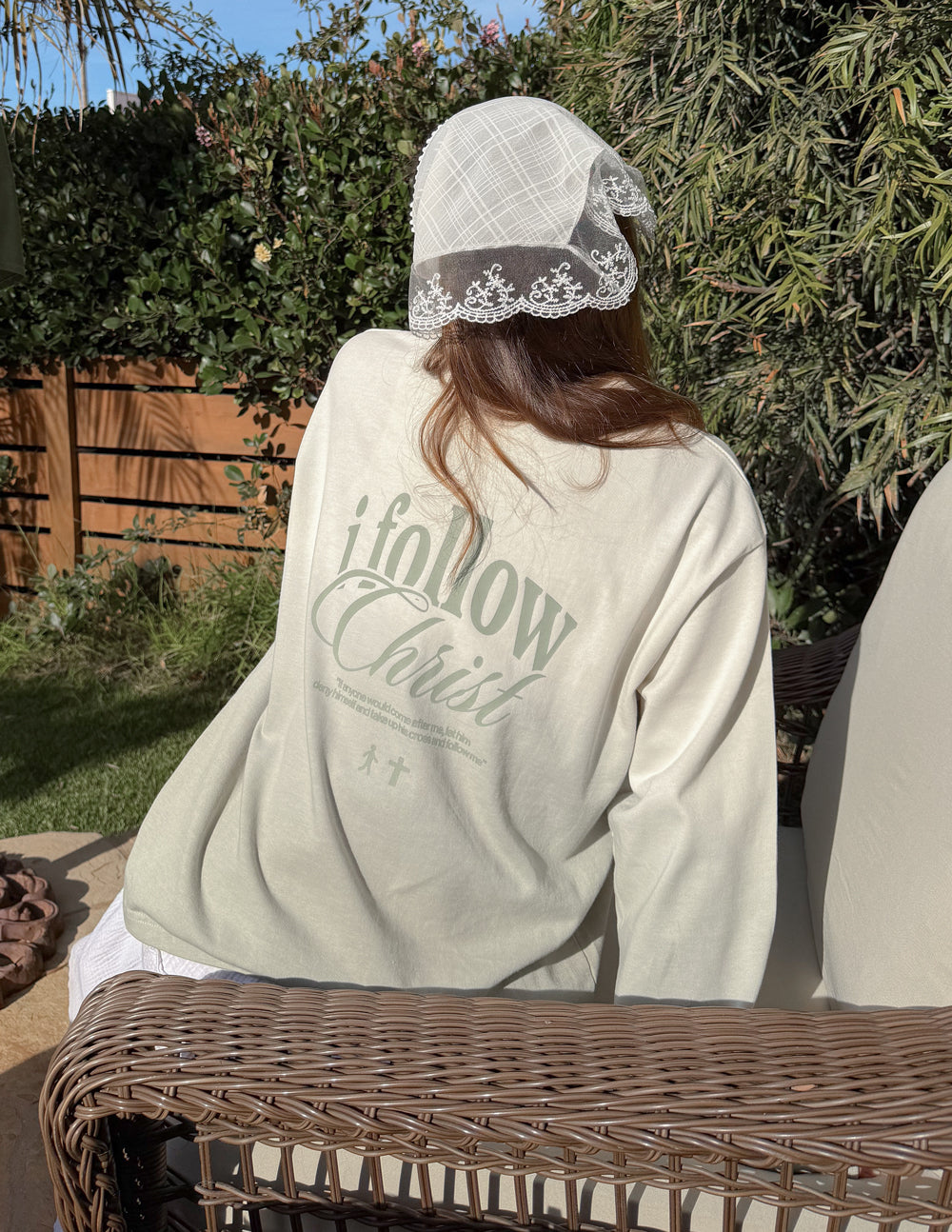 Light cream long-sleeve crewneck tee with 'i follow Christ' back graphic