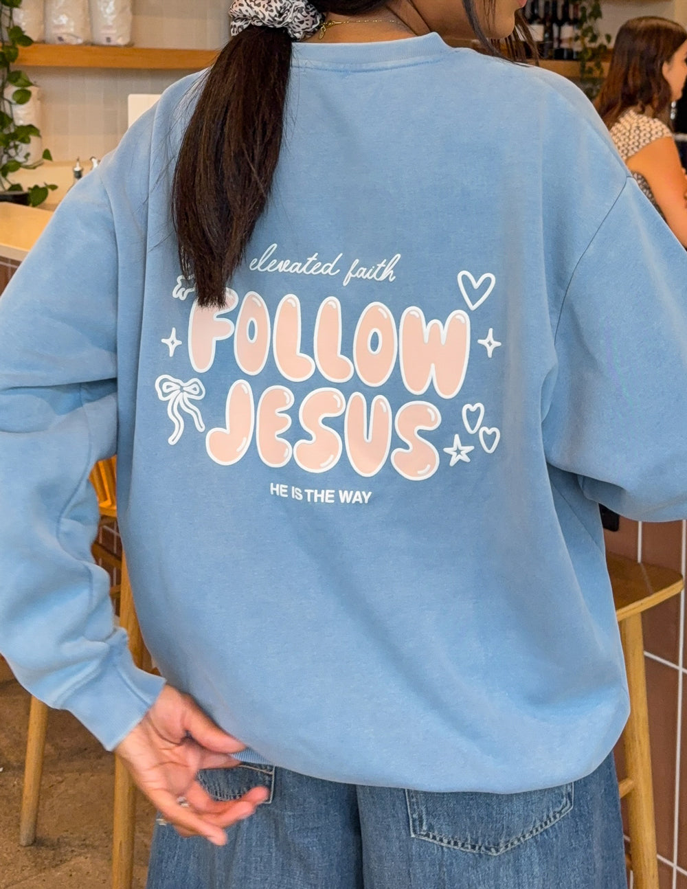 Light blue unisex crewneck sweatshirt, back “Follow Jesus” text with decorative stars