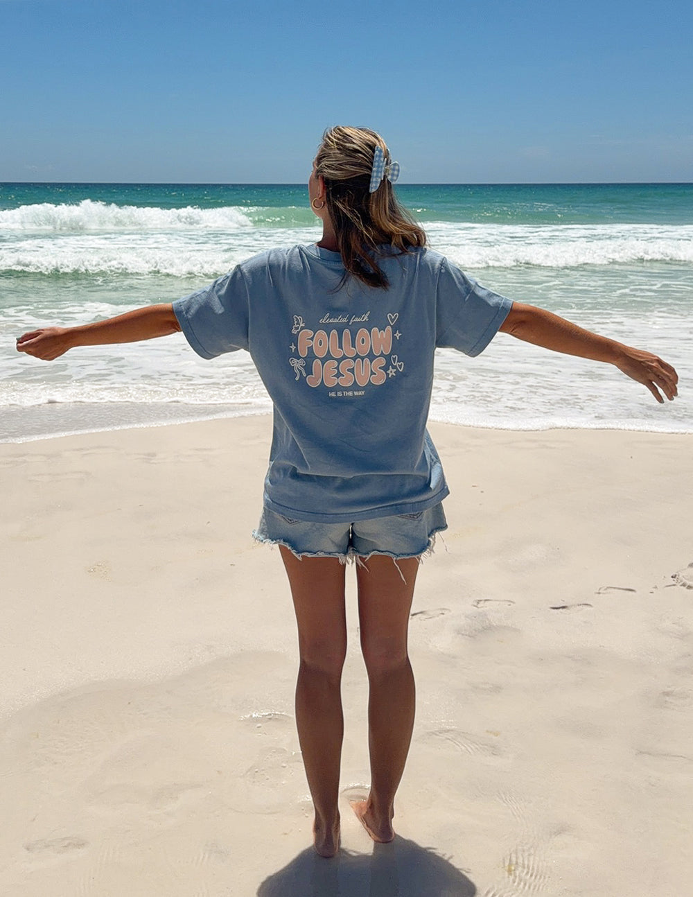 Unisex light blue T-shirt with short sleeves and centered "Follow Jesus" graphic on back