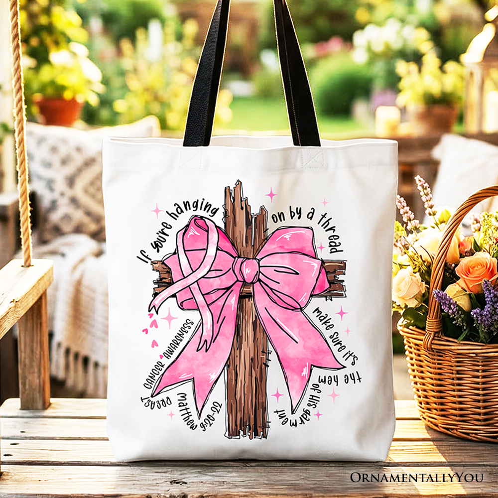 White cotton tote bag with large pink bow and ribbon tree graphic, black handles.