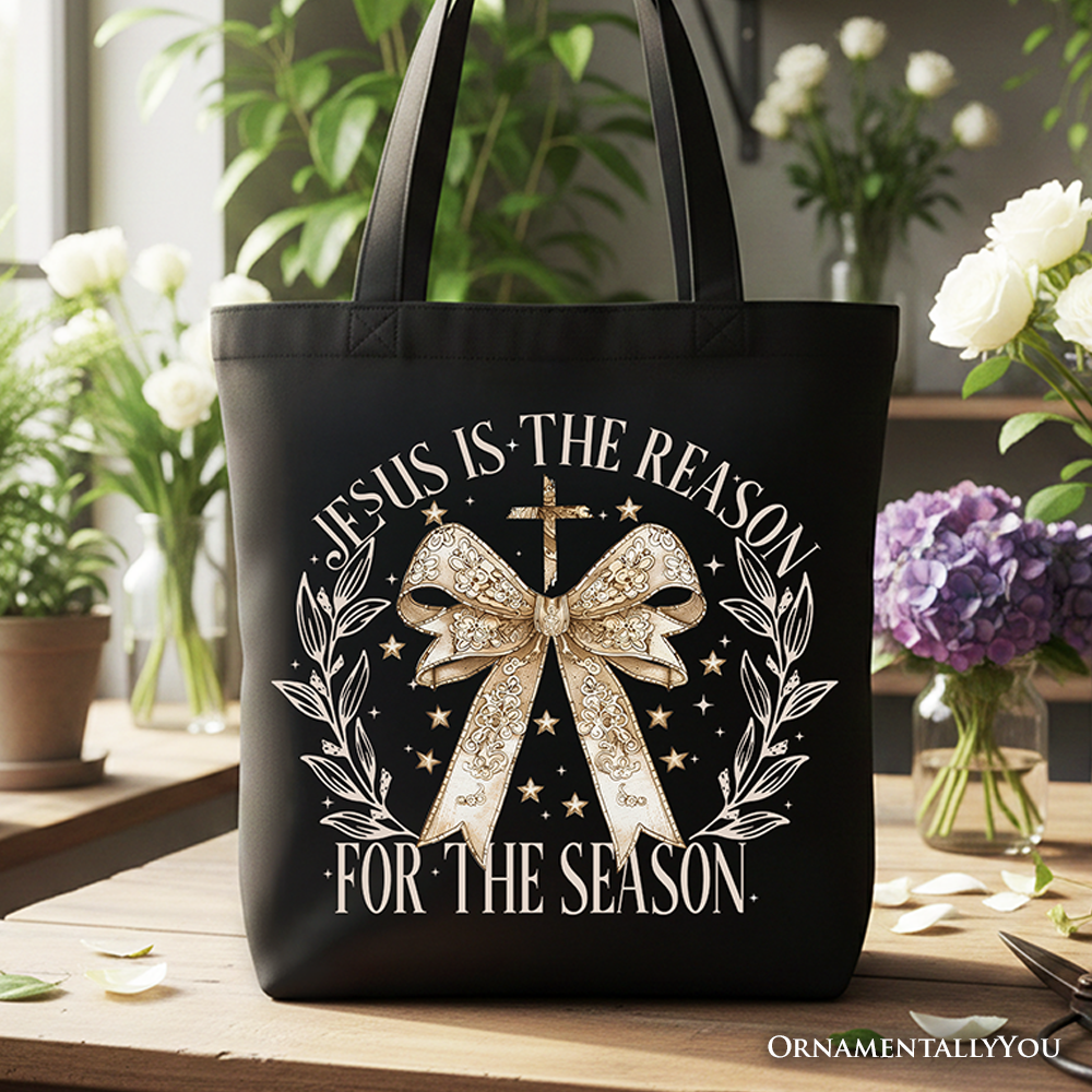 Black Christmas tote bag with gold bow centerpiece and “Jesus Is the Reason” text