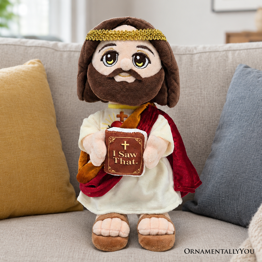 Plush Jesus toy in white robe and red cape, holding a small book that reads “I Saw That.”