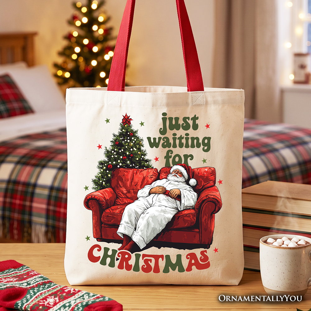 White tote bag with Santa-on-couch 'Just waiting for Christmas' print, red handles