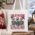 White cotton tote bag with colorful skeleton holiday graphic and red slogan; white handles