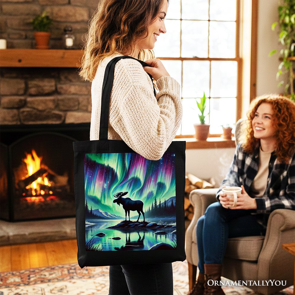 Black canvas tote bag with northern lights moose scene, shown in side view