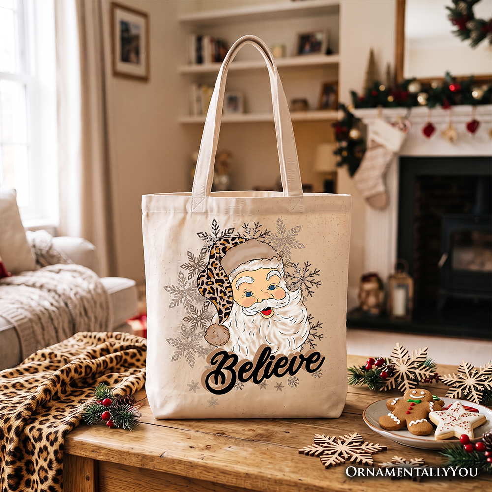 White tote bag with Santa “Believe” design, shown standing on a wooden surface