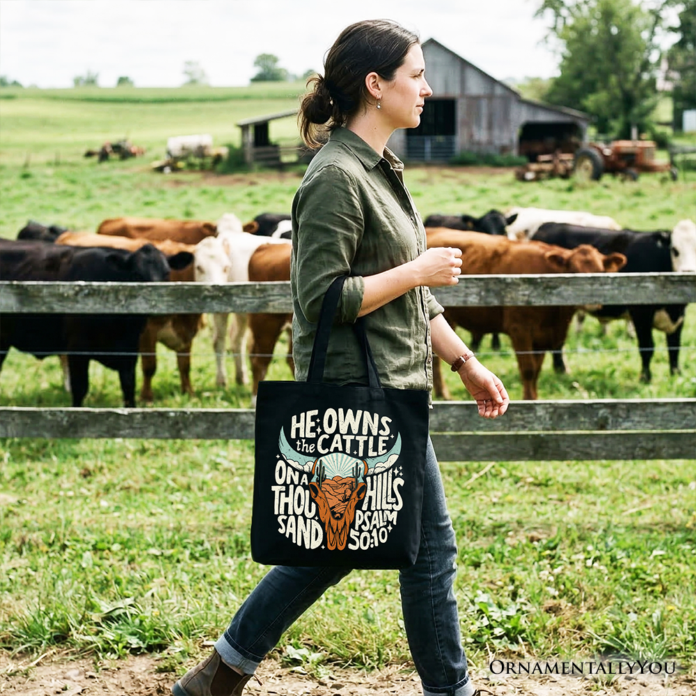 Black tote bag with “He Owns the Cattle” quote and bull head graphic, short handles