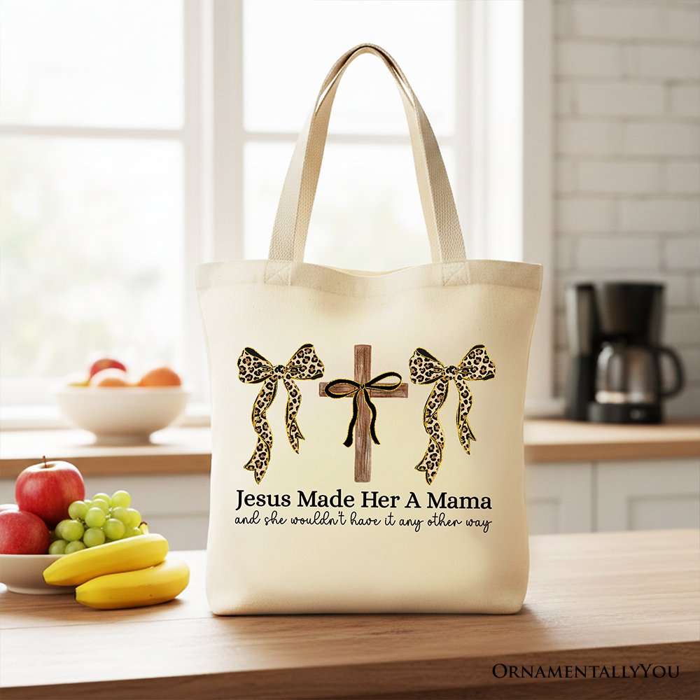 Light beige tote bag with short handles, leopard bow and cross faith graphic on front.