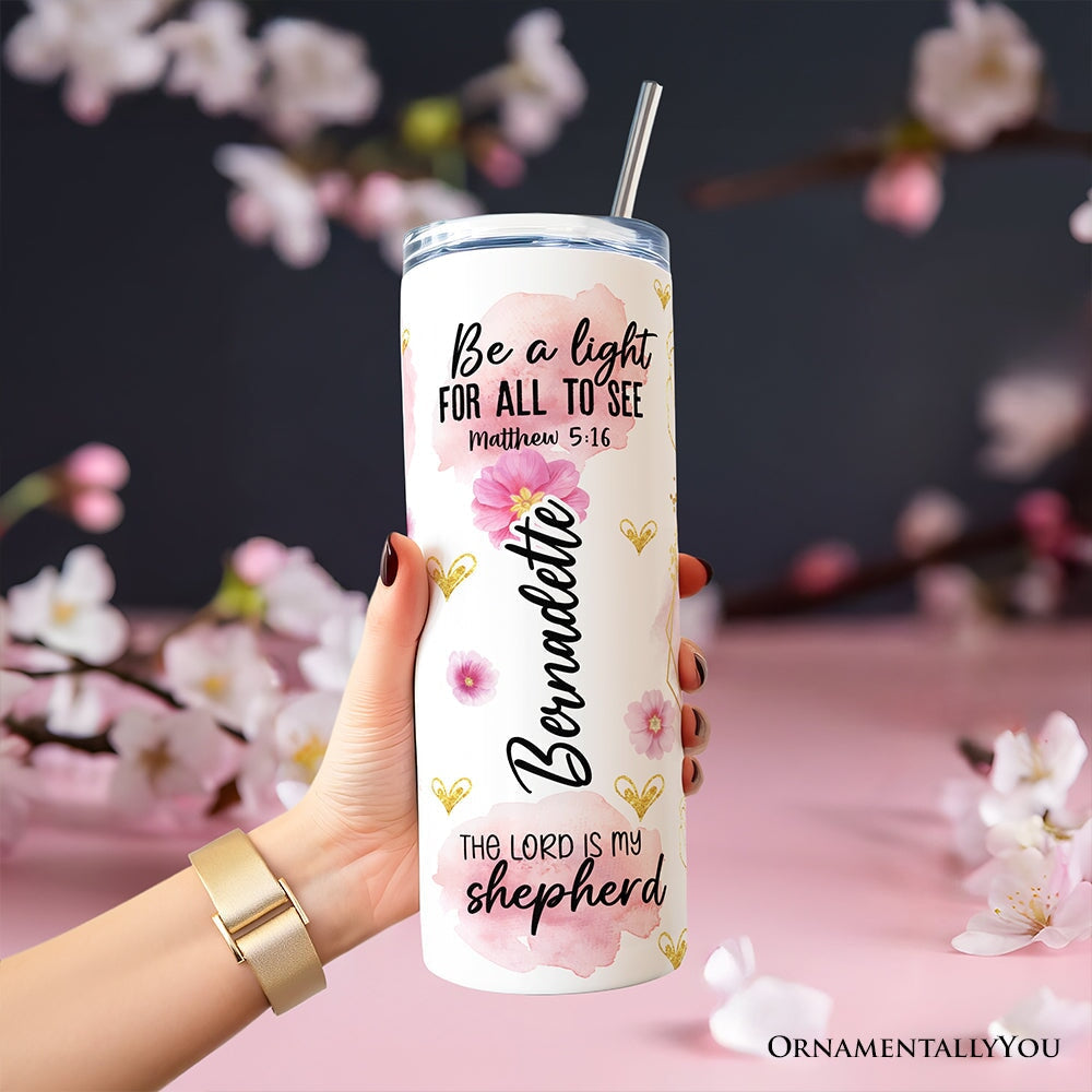 Pink floral Christian tumbler with lid and stainless steel straw, close-up with hand