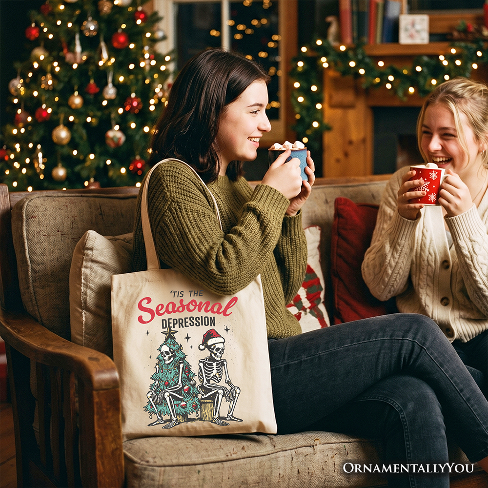 White cotton tote bag carried by hand, showing 'Tis the Seasonal Depression' illustration