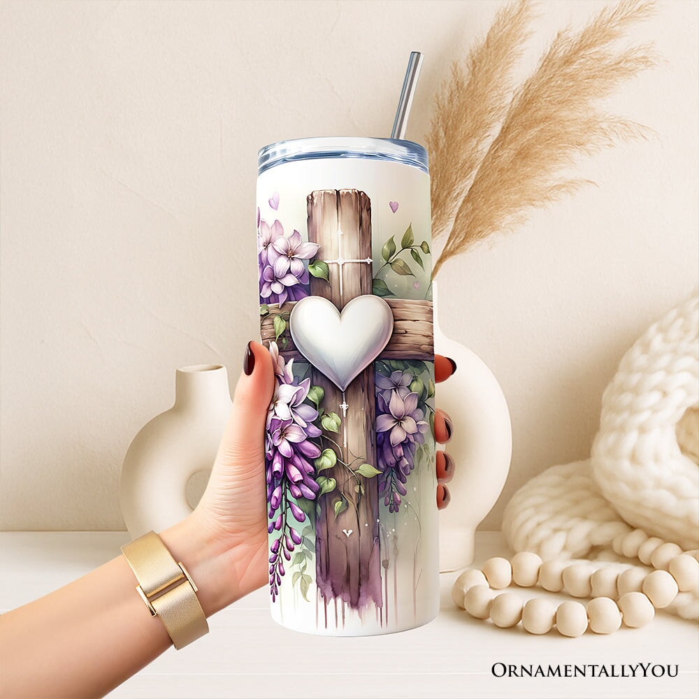 Hand holding purple wisteria tumbler with heart cross design and stainless straw