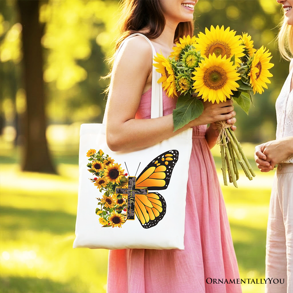 White tote bag with sunflower butterfly cross graphic, held close to camera