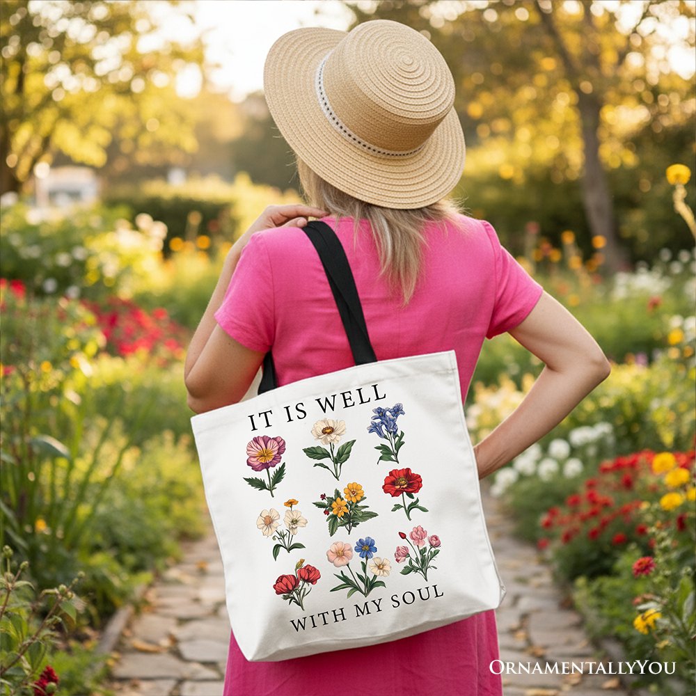 White canvas tote with black handles, floral 'IT IS WELL' and 'WITH MY SOUL' lettering.