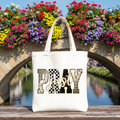 White tote bag with “Pray” patchwork graphic across the front