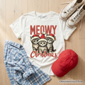 Kids white cat Christmas graphic t-shirt flat lay with plaid shirt, cap, and sneakers