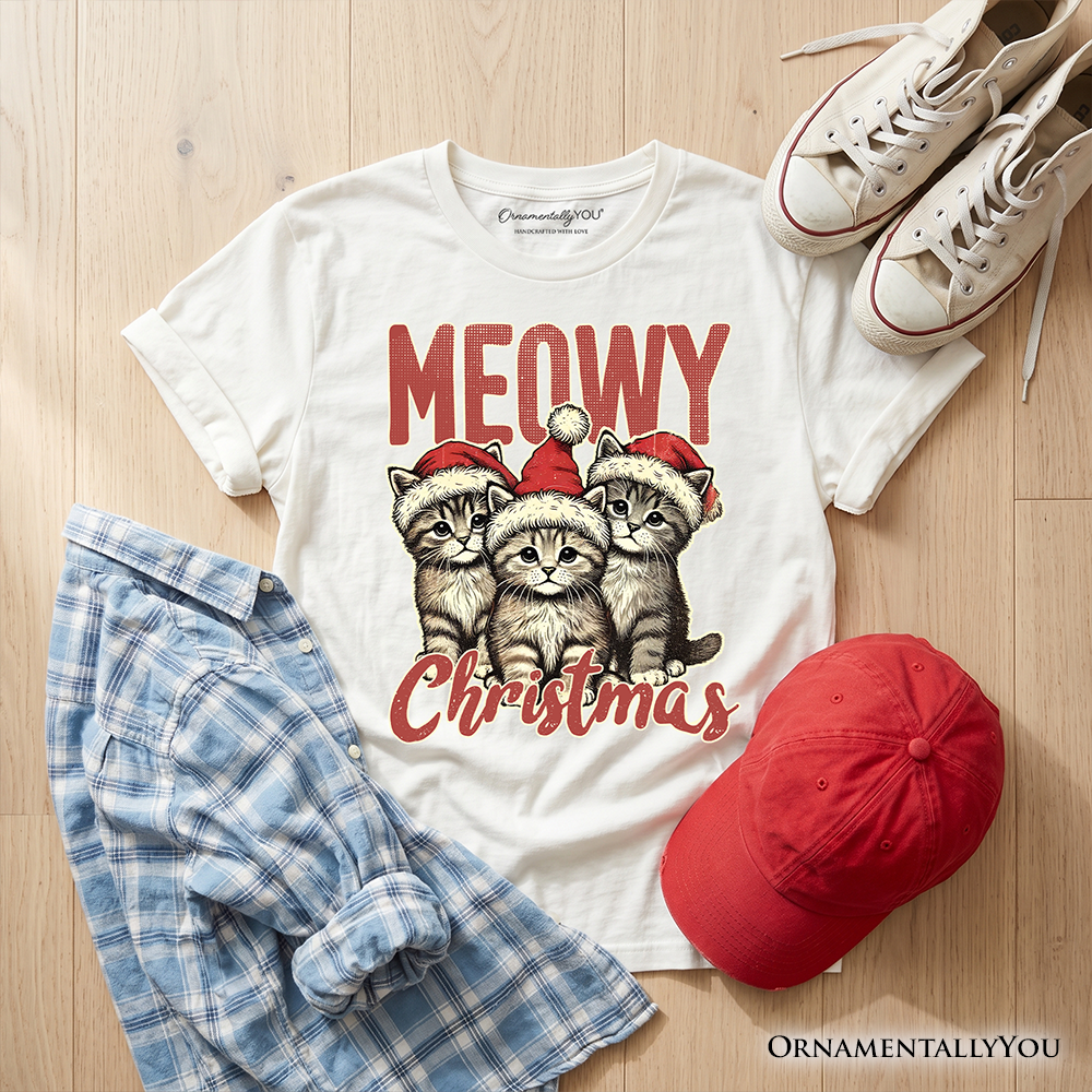 Kids white cat Christmas graphic t-shirt flat lay with plaid shirt, cap, and sneakers