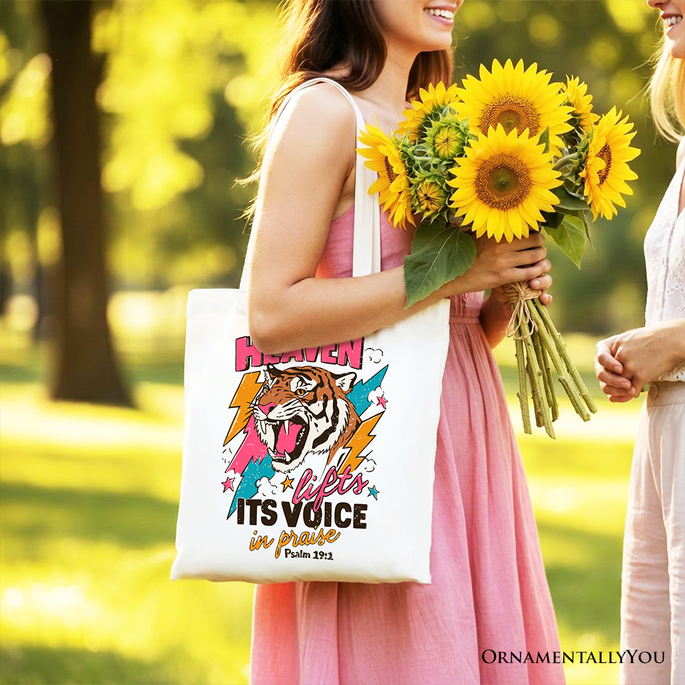 White tote bag held in hand with tiger graphic and “Its voice in praise” text.