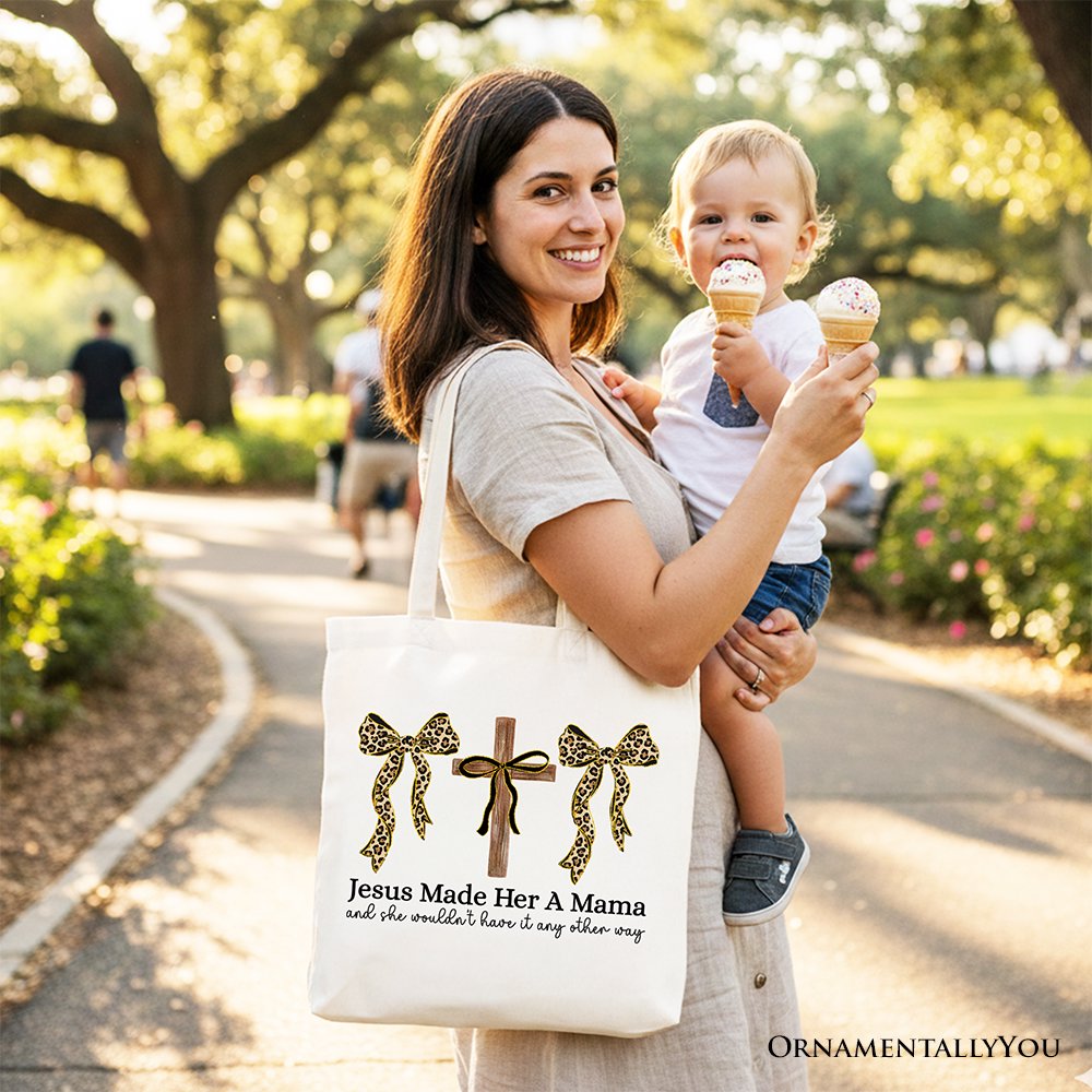 White tote bag with leopard bows and cross graphic, held outdoors by person.