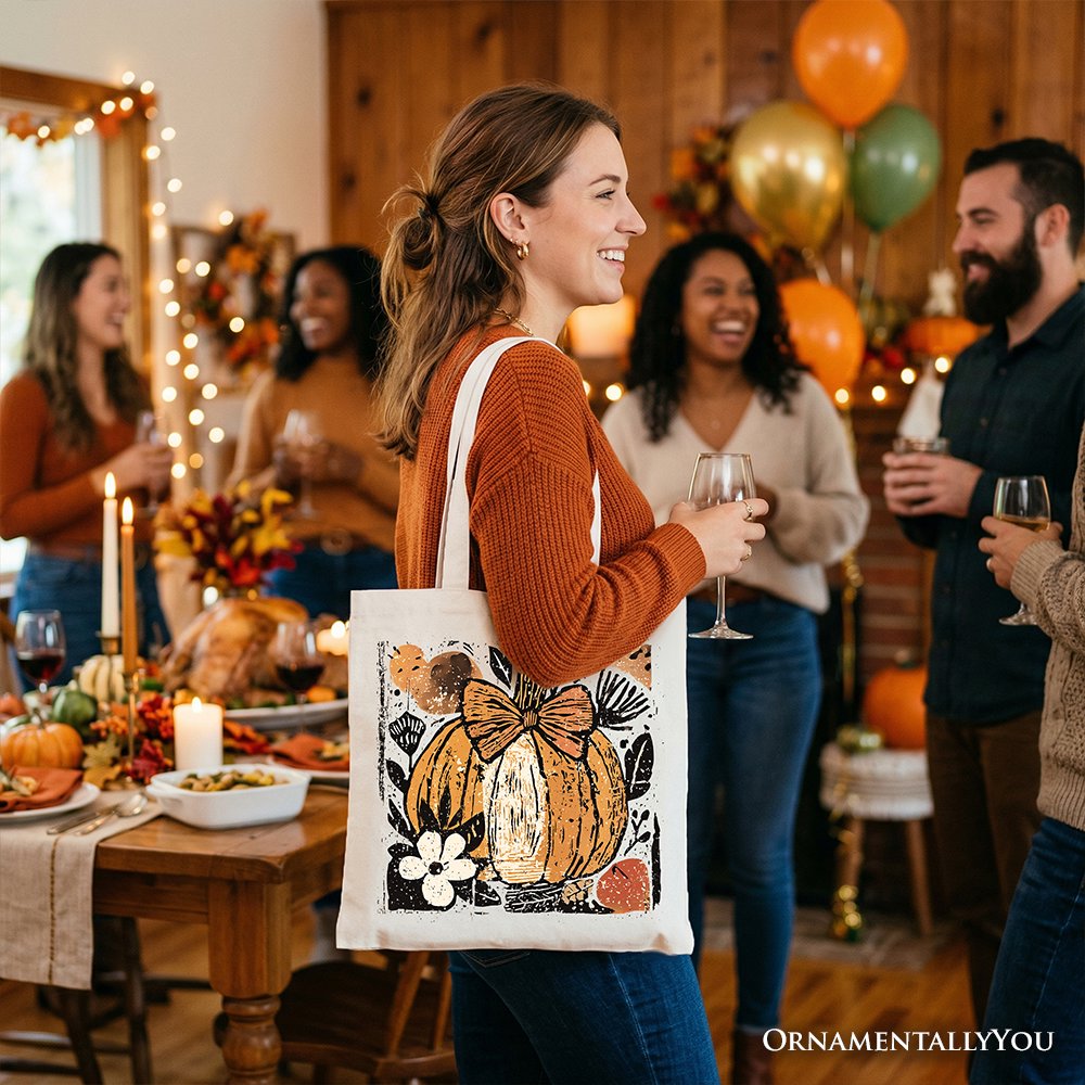 White canvas tote bag with pumpkin floral bow print, held at side